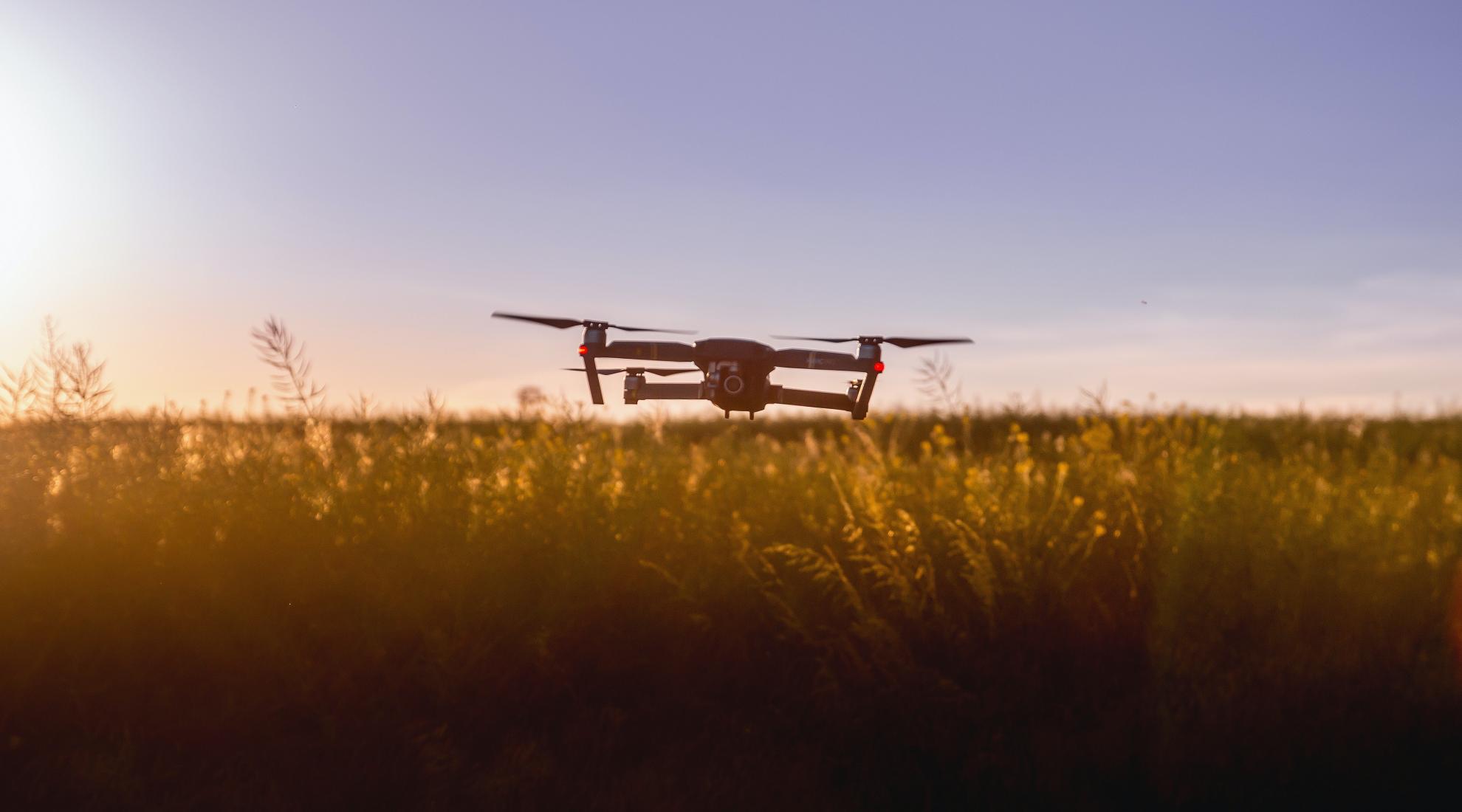 A quadcopter drone flying over agriculture land