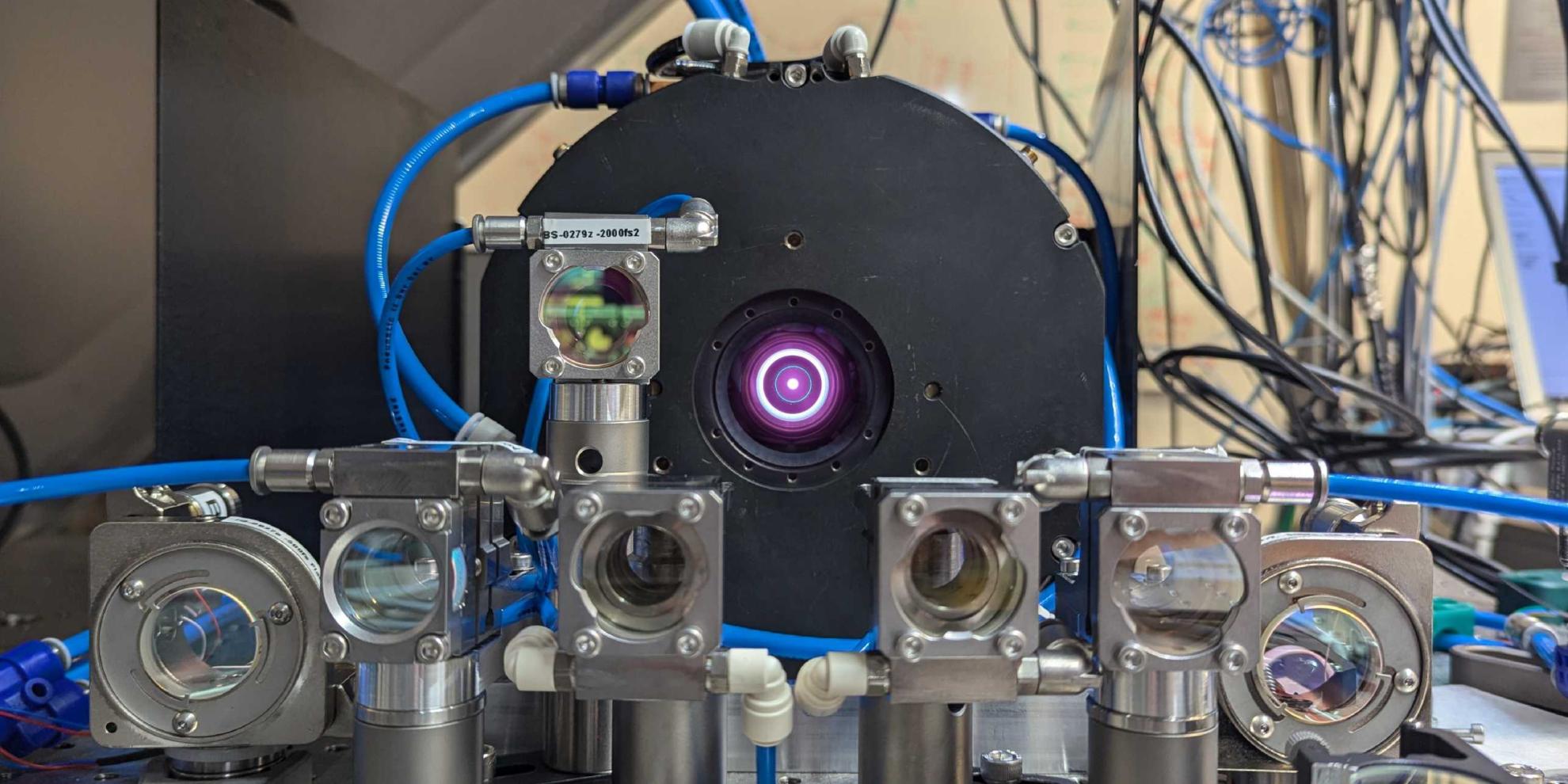 The laser can be seen in the centre of the image, with lenses and mirrors in the foreground that reflect and redirect the laser beam.